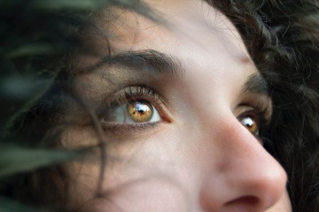 Eine Frau mit Locken hat leuchtende bernsteinfarbene Augen