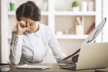 Erschöpfte Frau am Schreibtisch, nahe dem Burnout