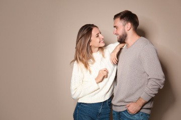 Chemie zwischen Mann und Frau, dargestellt anhand eines jungen Paares, welches in der Küche steht und sich gegenseitig anlächelt.