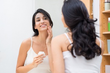 Eine Frau gibt Creme gegen Falten durch trockene Haut in ihr Gesicht