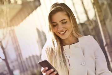 Eine Frau schaut auf ihr Smartphone und lächelt