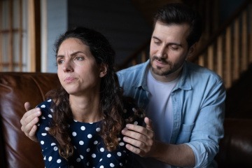 Eine Frau wendet sich auf der Couch wütend von einem Mann ab