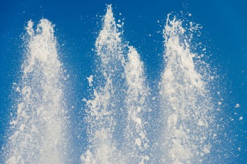 Weiße Fontänen spritzen vor einem blauen Hintergrund