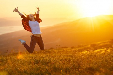 Frau macht einen Luftsprung im Sonnenuntergang