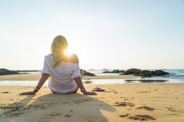 Eine Frau sitzt entspannt am Meer