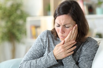 Eine Frau hat Schmerzen wegen einer Erkrankung im Mund