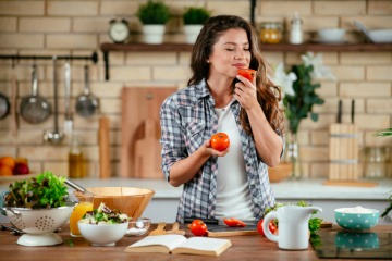 Kochende Frau riecht an einer Tomate