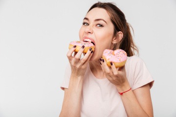 Frau isst aus Stress Doughnuts.