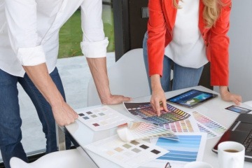 Ein Mann und eine Frau wählen Farben aus einem Farbkatalog aus
