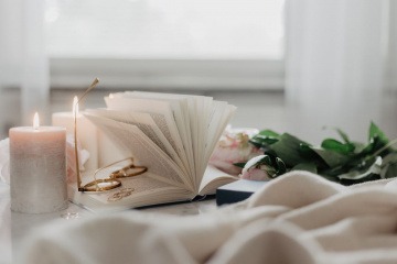 Ein aufgeschlagenes Buch, Ringe und Kerzen