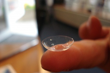 Auf einem Finger ist eine Kontaktlinse