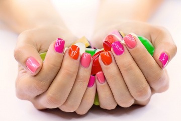 Fingernägel sind in Orange und Pink lackiert