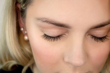 Ein blondes Mädchen mit Zahnspange hat lange Wimpern