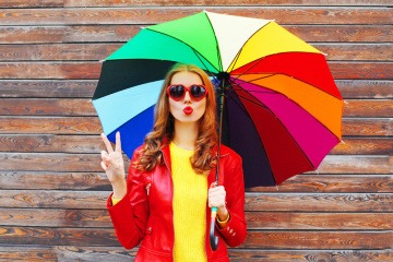 Eine Frau hält einen bunten Regenschirm in ihrer Hand