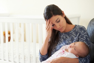 Eine Frau hält Ihr Baby im Arm und muss erst ihr Geburtstrauma verarbeiten