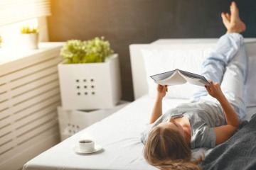 Eine Frau liegt im Bett und liest ein Buch