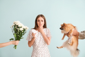 Einer Frau mit Allergie werden ein Blumenstrauß und ein Hund gereicht