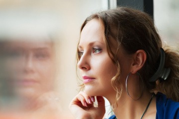 Eine Frau sieht nachdenklich aus dem Fenster raus