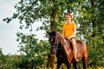 Eine Frau reitet ohne Sattel auf einem schwarzen Pferd