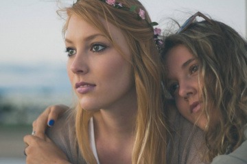 Zwei Frauen umarmen sich und blicken bewusst drein