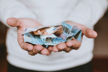 In einer Hand liegen Geldscheine