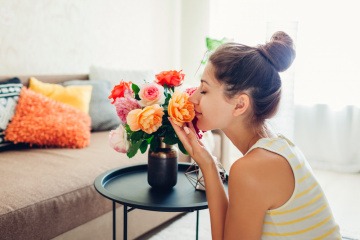 Frau reicht an einem Blumenstrauß.