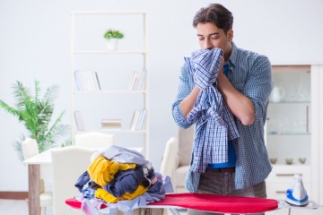 Ein junger Mann riecht genussvoll an seiner Wäsche