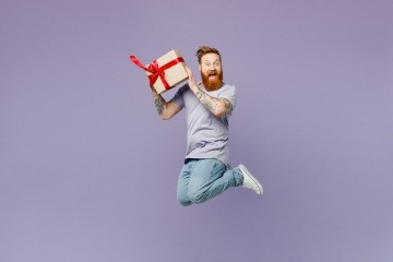 Geschenkidee für Mann - Mann springt mit Geschenk in der Hand vor Freude in die Luft.
