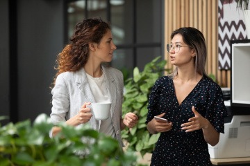 Zwei Frauen halten Smalltalk in der Kantine ihrer Arbeitsstelle.