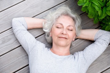 Eine ältere Frau liegt glücklich auf einem Holzboden