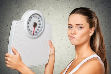 Eine Frau hält eine Waage und muss den Gewichts- und Stoffwechsel optimieren