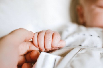 Schlafendes Baby hält finger einer erwachsenen Person