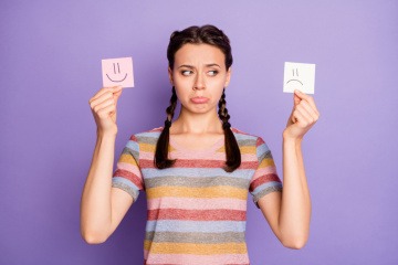 Junge Frau mit zwei Zetteln mit Smileys in der Hand. 