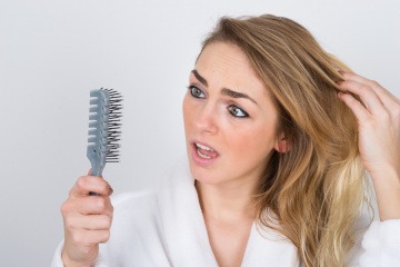 Eine Frau hält eine Bürste mit vielen Haaren darin in der Hand
