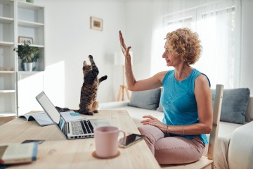 Berufstätige Frau gibt ihrer Katze ein High-Five.