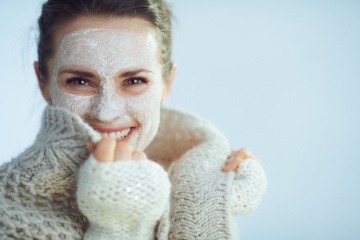 Frau mit Wollpulli und Hautpflege-Maske