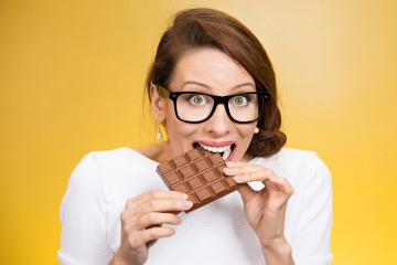 Frau mit Heißhunger beißt in Schokoladentafel
