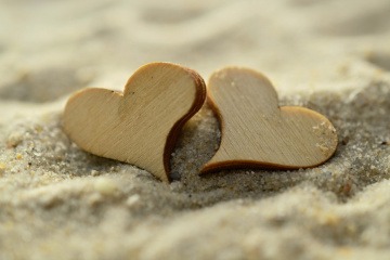 Herzen aus Holz liegen im Sand