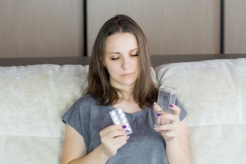 Eine Frau nimmt Tabletten als Hilsmittel gegen Allergien