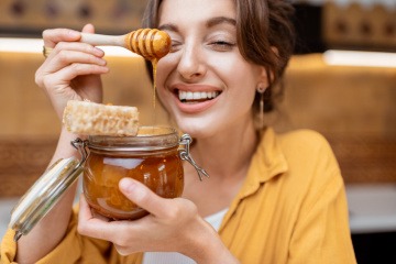 Frau mit Honig vor dem Gesicht