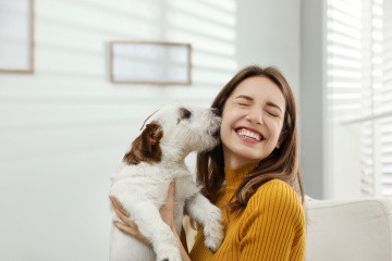 Hund leckt das Gesicht einer Frau