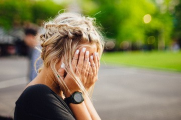 Eine Frau hält sich wegen Hautirritationen im Gesicht die Hände vor