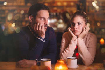 Eine Frau und ein Mann in einer Bar schauen sich gelangweilt an