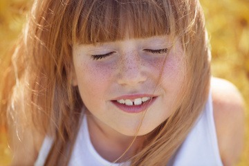 Ein Kind lächelt im Sommer und hat Pigmentflecken