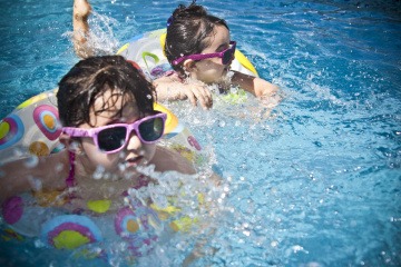 Kinder sind im Schwimmbad und tragen Sonnenschutz