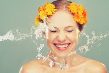 Eine Frau spritzt zur Körperpflege Wasser ins Gesicht