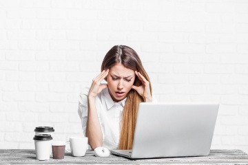 Frau mit Kopfschmerzen am Arbeitsplatz.