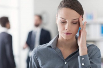 Eine Frau hat Kopfweh nach Mobbing am Arbeitsplatz 