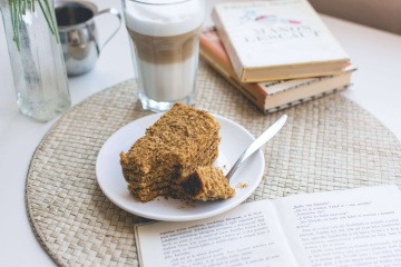 Neben einem Kuchen mit Nüssen steht eine Tasse Kaffee