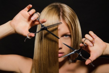 Eine Frau schneidet ihre langen Haare mit einer Schere mittellang